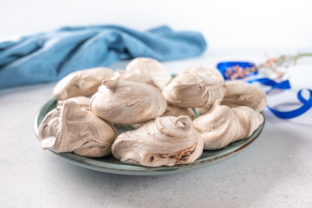 Homemade dessert of egg meringue on a ceramic plate on a light background at the back is a blue