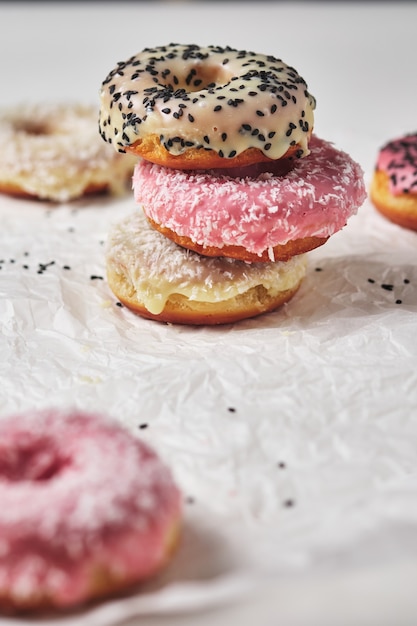 Homemade donuts with coconut and black sesame seeds in multi-colored glaze