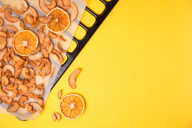 Homemade dried organic apple sliced on yellow table.