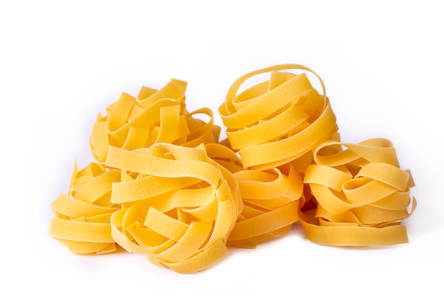 Photo homemade egg pasta tagliatelle. raw nest noodles, uncooked ribbon fettuccine, dry long rolled macaroni isolated on white background top view