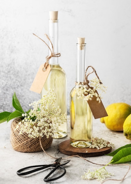 Homemade elderflower syrup in glass bottles for summer drink with elder flower buds and lemon