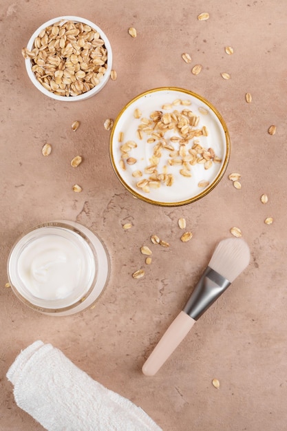 Homemade facial mask or creamy scrub with cereal made of yogurt and oats flake on a beige background