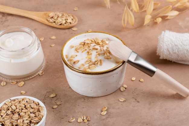 Homemade facial mask or creamy scrub with cereal made of yogurt and oats flake on a beige background