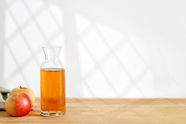 Homemade fresh Apple cider juice in glass and fresh apples on wooden table Window shadow Copy space