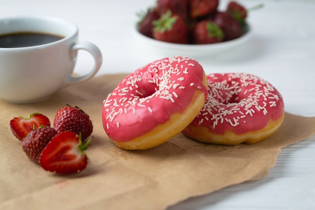 Homemade fresh baked donuts with strawberry pink frosting and black coffee