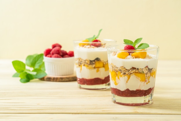 homemade fresh mango and fresh raspberry with yogurt and granola - healthy food style