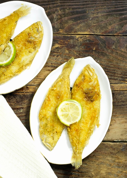 homemade fried fish lemon sole in white plate on wood table