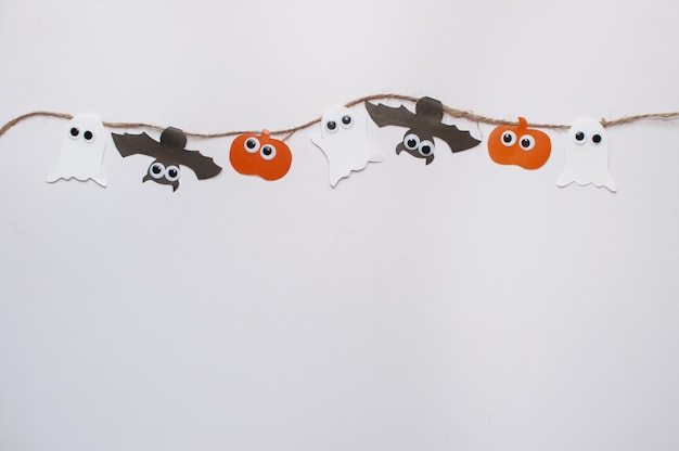 Homemade garland on a jute rope made of pumpkin bat and ghosts with eyes