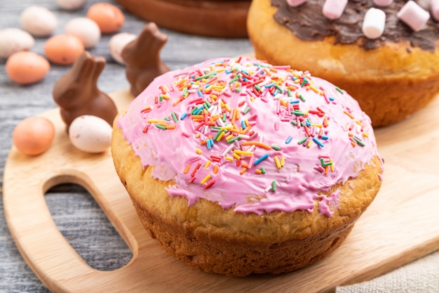 Homemade glazed and decorated easter pies on a gray wooden surface and linen textile. Side view, close up.