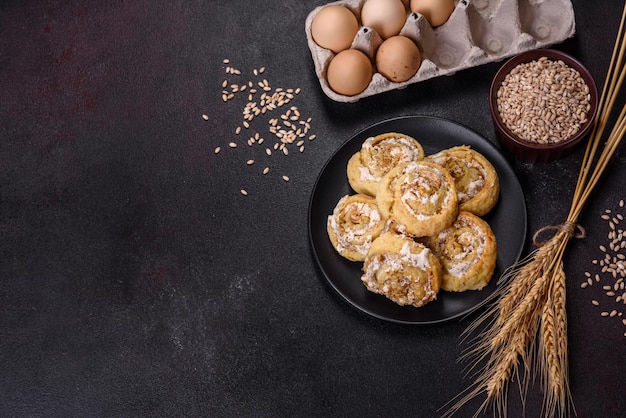 Homemade glazed puff pastry cinnamon rolls with custard and raisins over old dark concrete background