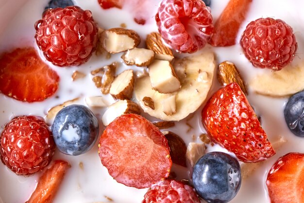 Homemade granola in a bowl, strawberries, almonds, blueberries, raspberry, organic milk - prepared natural dietary breakfast. Close-up. Top view