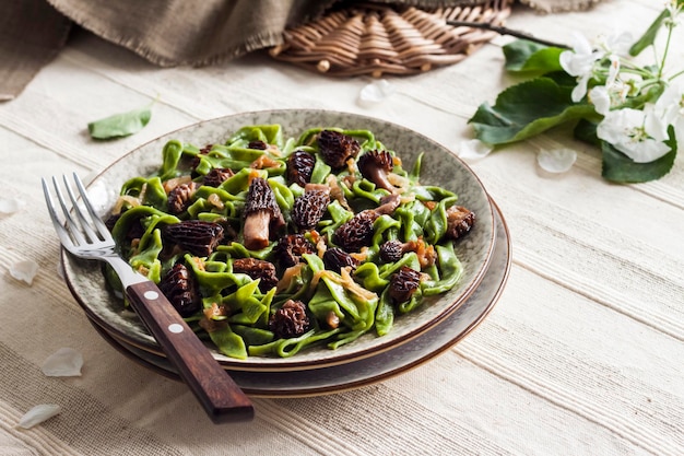 Homemade green nettle pasta with fried spring morel mushrooms