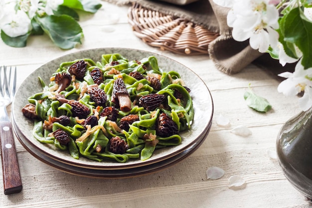 Homemade green nettle pasta with fried spring morel mushrooms