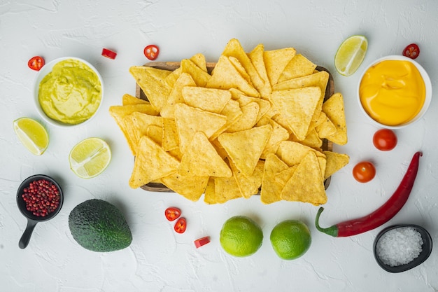 Homemade guacamole and cheese dip with nachos, on white table, top view or flat lay