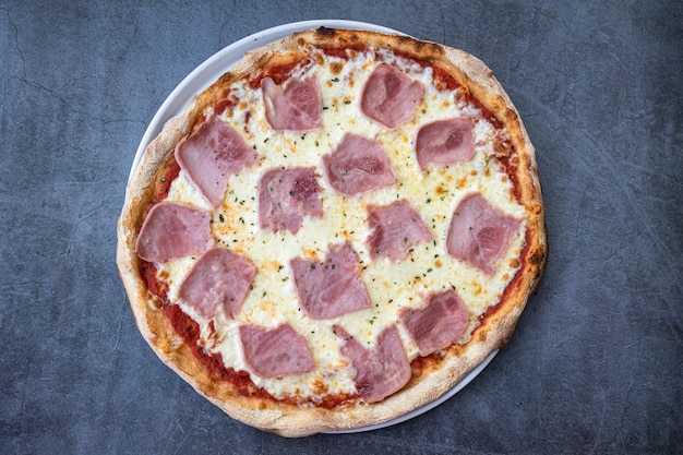 Homemade ham and cheese pizza on a rustic background top view