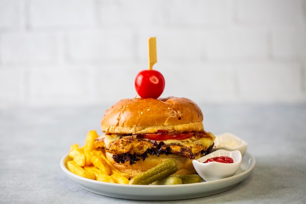 Homemade hamburger served with french fries. It looks delicious prepared with onions, hamburger patties, cheddar cheese and ham.