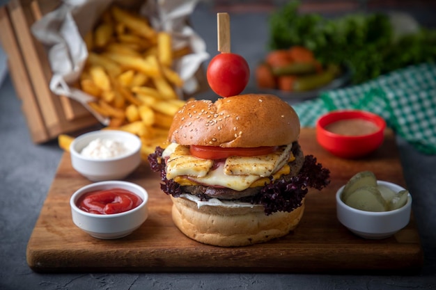 Homemade hamburger served with french fries. It looks delicious prepared with onions, hamburger patties, cheddar cheese and ham.