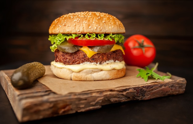 Homemade hamburger with lettuce, tomato, cheese and cucumber on a cutting board