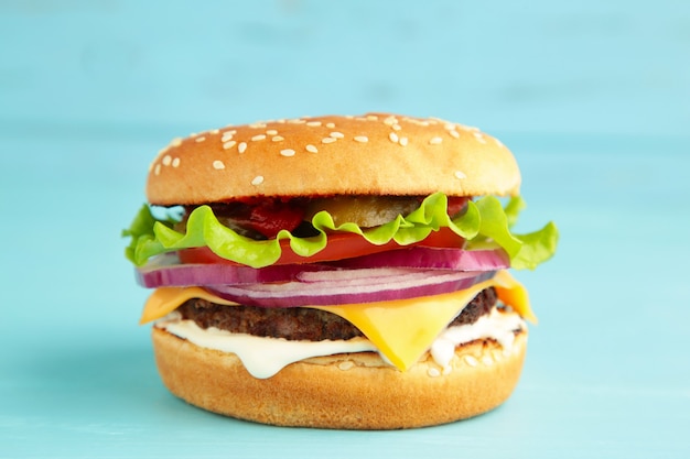 Homemade hamburger with vegetables on blue.