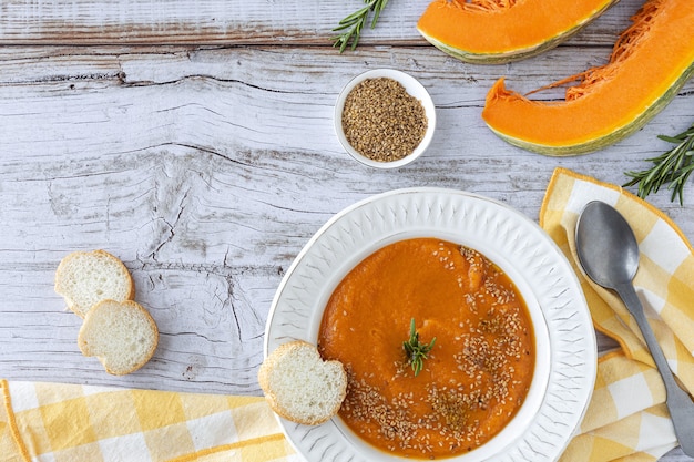 Homemade and healthy pumpkin cream with bread from above on  wooden table. Flat lay