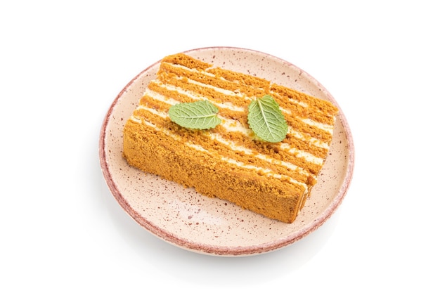 Homemade honey cake with milk cream and mint isolated on white surface