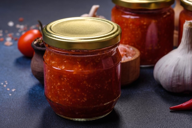 Homemade hot tomato sauce adjika in jars Tomatoes chilli pepper garlic and herbs