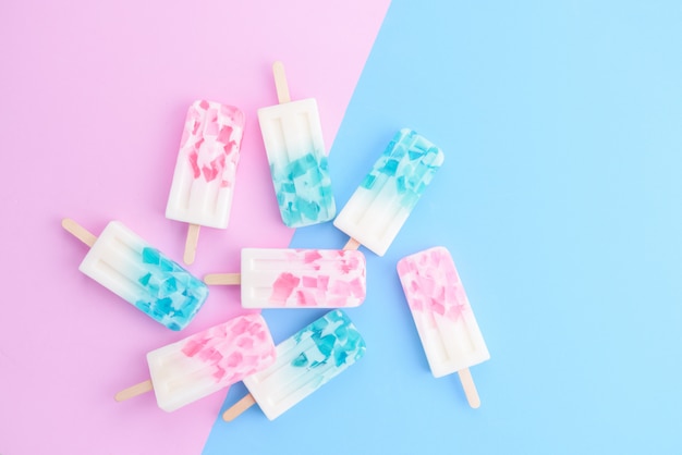 Homemade Ice cream sticks , popsicle , ice pop or freezer pop on blue and pink pastel colors background