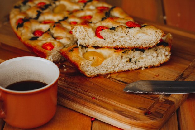 Homemade Italian Focaccia, with tomato and olive oil on a rustic wooden background.