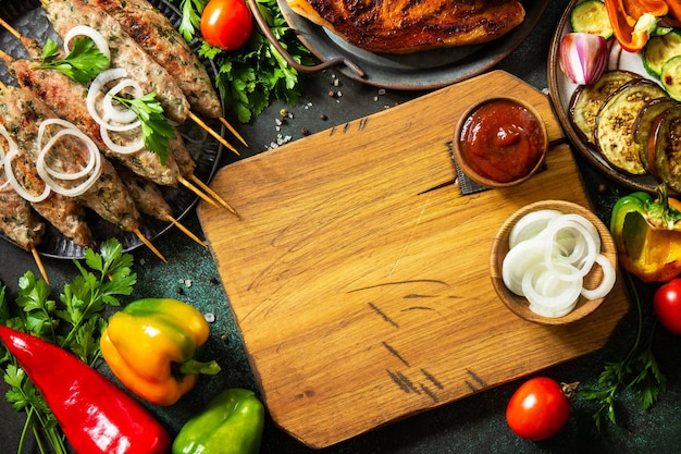 Homemade Kofta kebabs grilled steak and grilled vegetables on a dark stone tabletop Top view