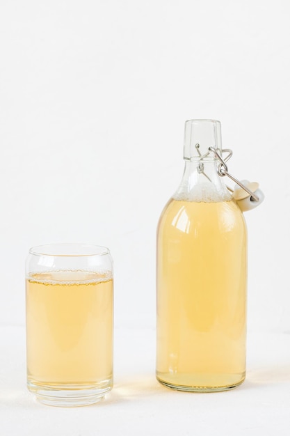 Homemade kombucha fermented drink in glass and bottle on white background Heathy probiotic beverage