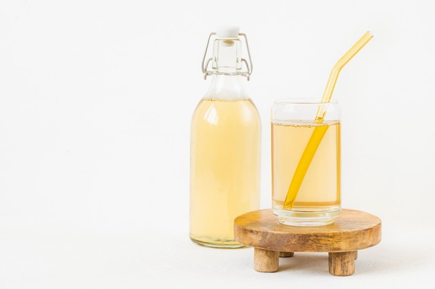 Homemade kombucha fermented drink in glass and bottle on white background Heathy probiotic beverage