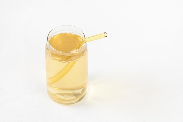 Homemade kombucha fermented drink in glass and straw on white background Heathy probiotic beverage