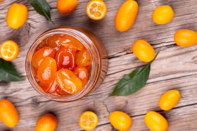 Homemade kumquat jam in jar and fresh kumquats, top view