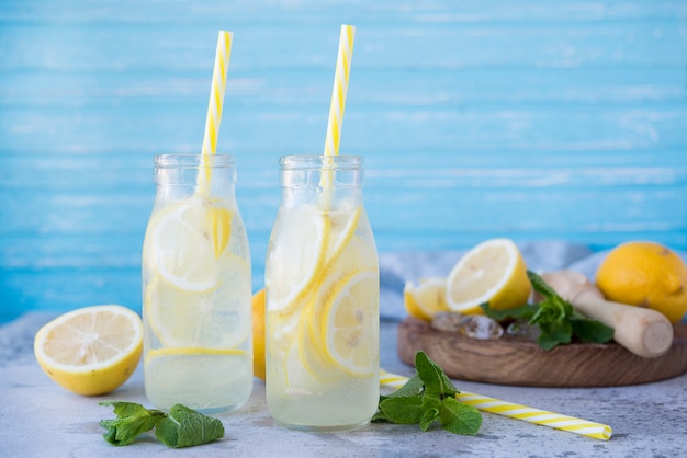 Homemade lemonade with lemons and mint in glass bottles