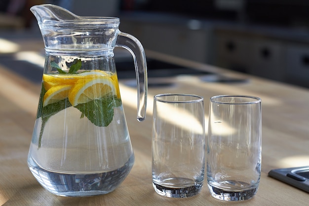 Homemade lemonade with lemons on a wooden table, soft focus.