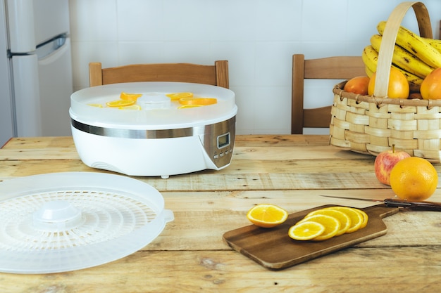 Homemade machine to dehydrate food with orange slices on kitchen table.