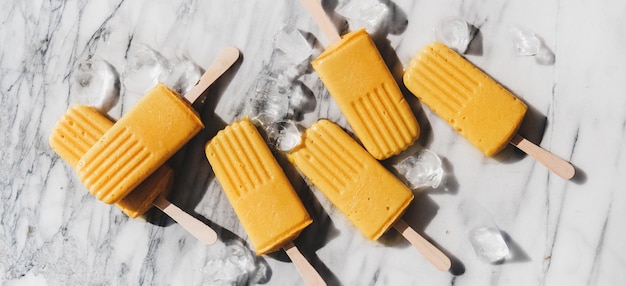 Photo homemade mango smoothie vegan popsicles over marble background wide composition