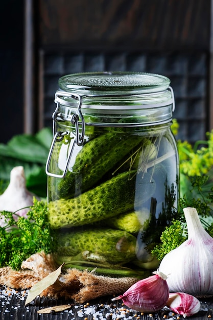 Homemade marinated cucumbers with dill and spices in a glass jar on a brown background selective focus