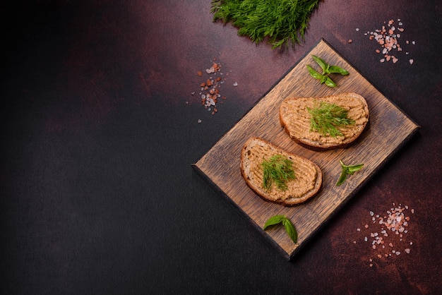 Homemade meat snack liver pate with toast on a dark concrete background