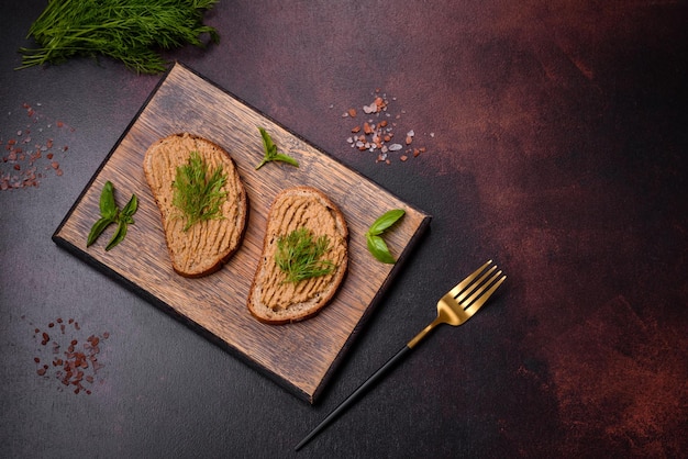 Homemade meat snack liver pate with toast on a dark concrete background