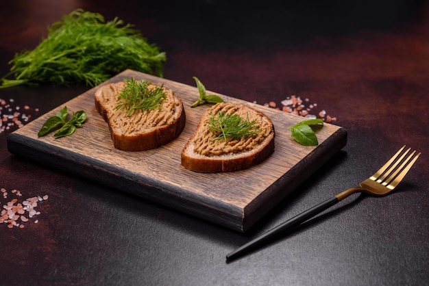 Homemade meat snack liver pate with toast on a dark concrete background