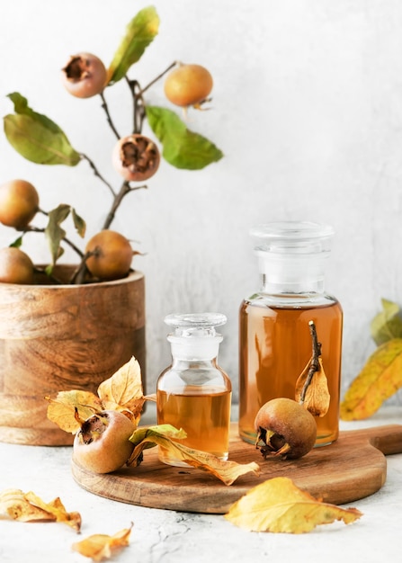 Homemade medlar fruit syrup or juice in pharmacy glasses on wooden cutting board