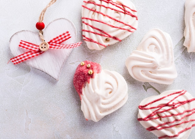 Homemade meringues in heart shape on light stone surface. Valentines day concept, top view, copy space