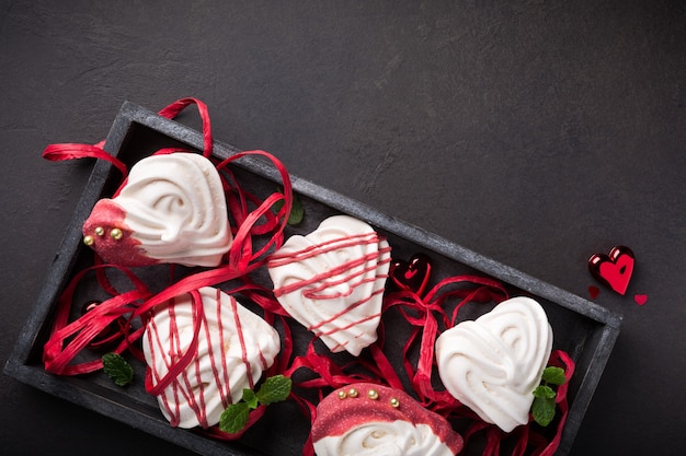 Homemade meringues in heart shape in old wooden box for Valentine's day, top view, copy space