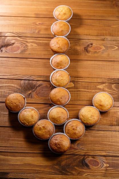 Homemade muffins in paper wrap on wooden board