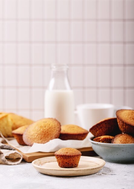 Homemade muffins served with milk in a bottle on white texture background