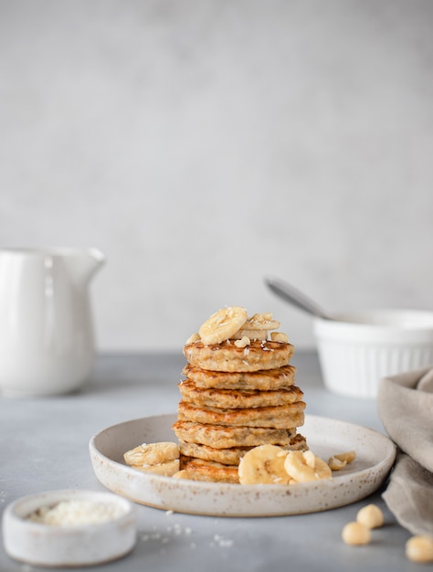 Homemade oat pancakes with banana and nuts gray surface,