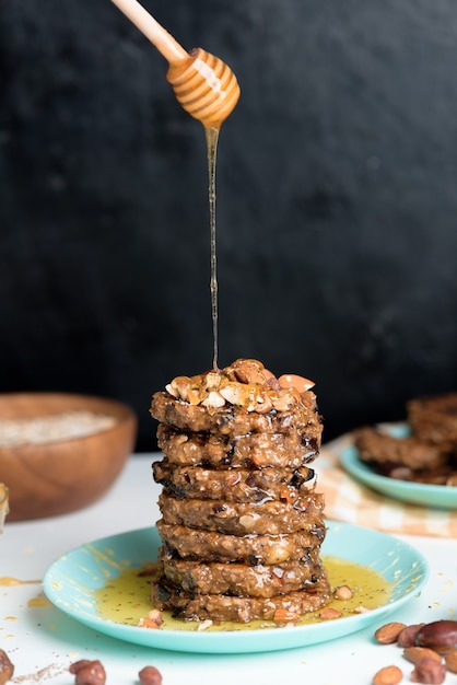 Homemade oatmeal banana pancakes with chia seeds, almonds, prunes and dates, drizzled with honey and crushed nuts