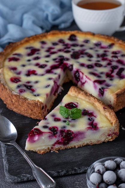 Homemade open blackcurrant shortbread pie on a slate plate on dark gray background