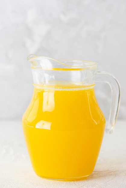 Homemade orange lemonade in a jug on a gray background Selective focus